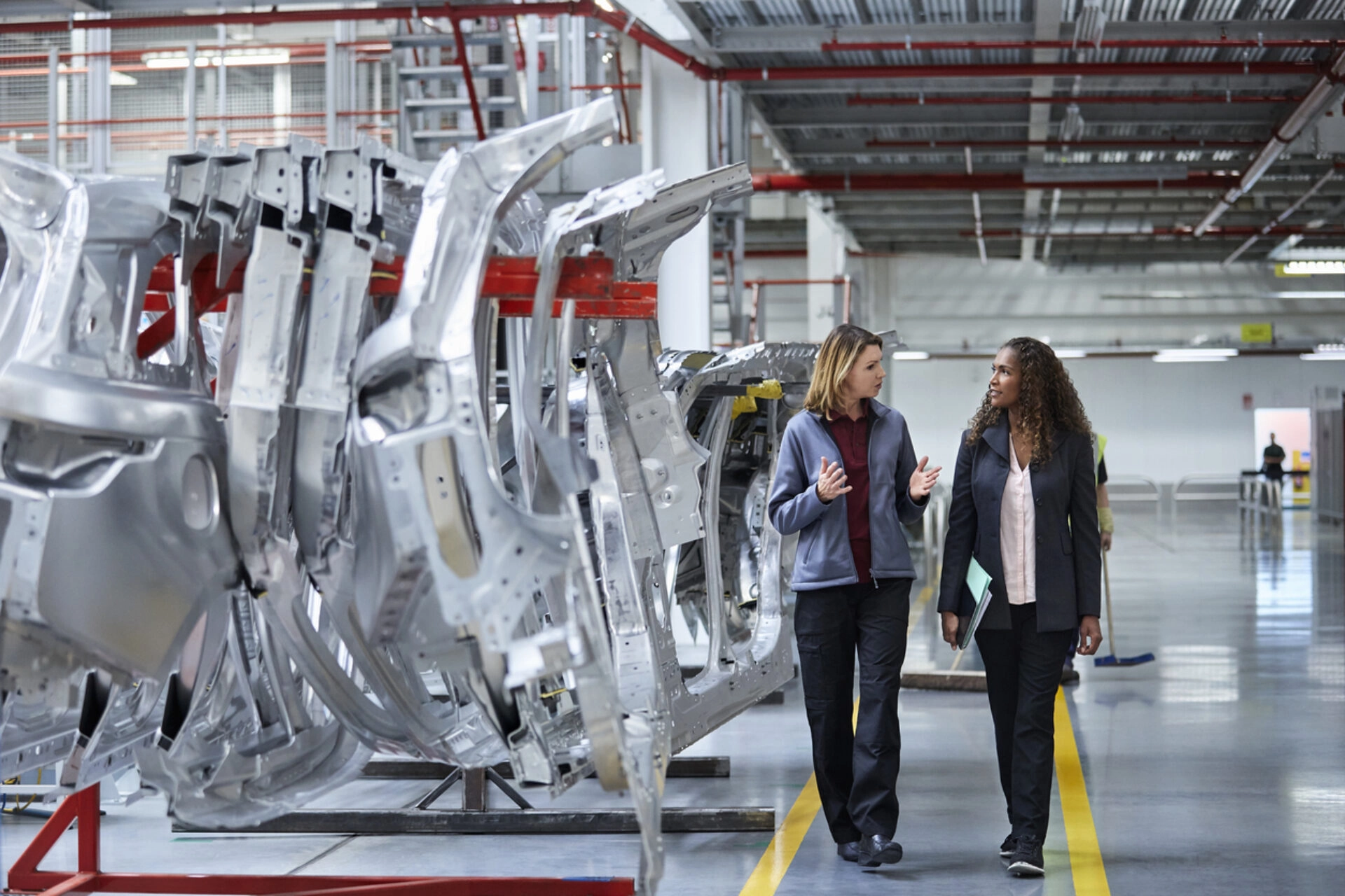 Engineers walking while discussing by car chassis